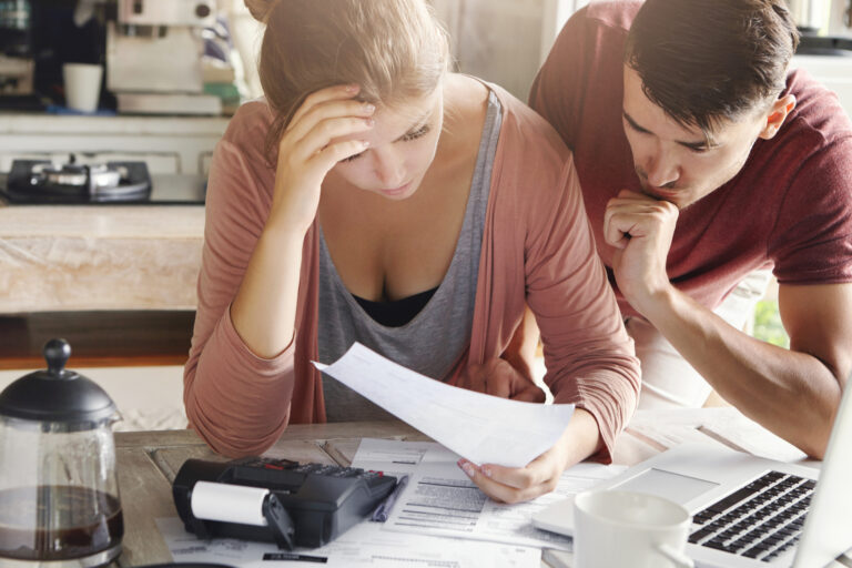 jeune couple stressé qui se prend la tête à calculer ses impots